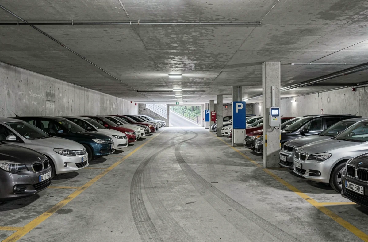 Vue intérieure d'un parking couvert en centre-ville avec bornes de paiement, places délimitées et signalétique bleue de stationnement