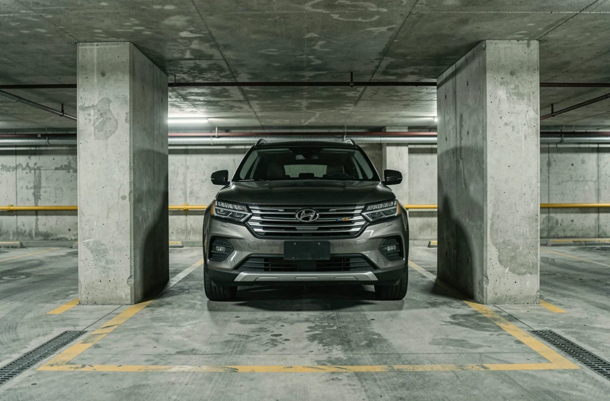 Grand SUV garé avec très peu d'espace dans un parking souterrain urbain aux piliers étroits