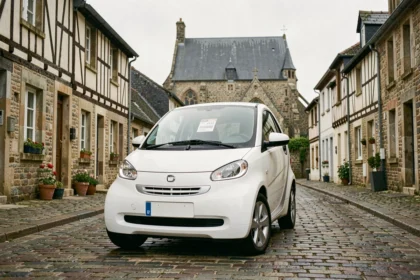 Voiture sans permis d'occasion blanche garée sur une rue pavée en Bretagne avec des façades à colombages en arrière-plan